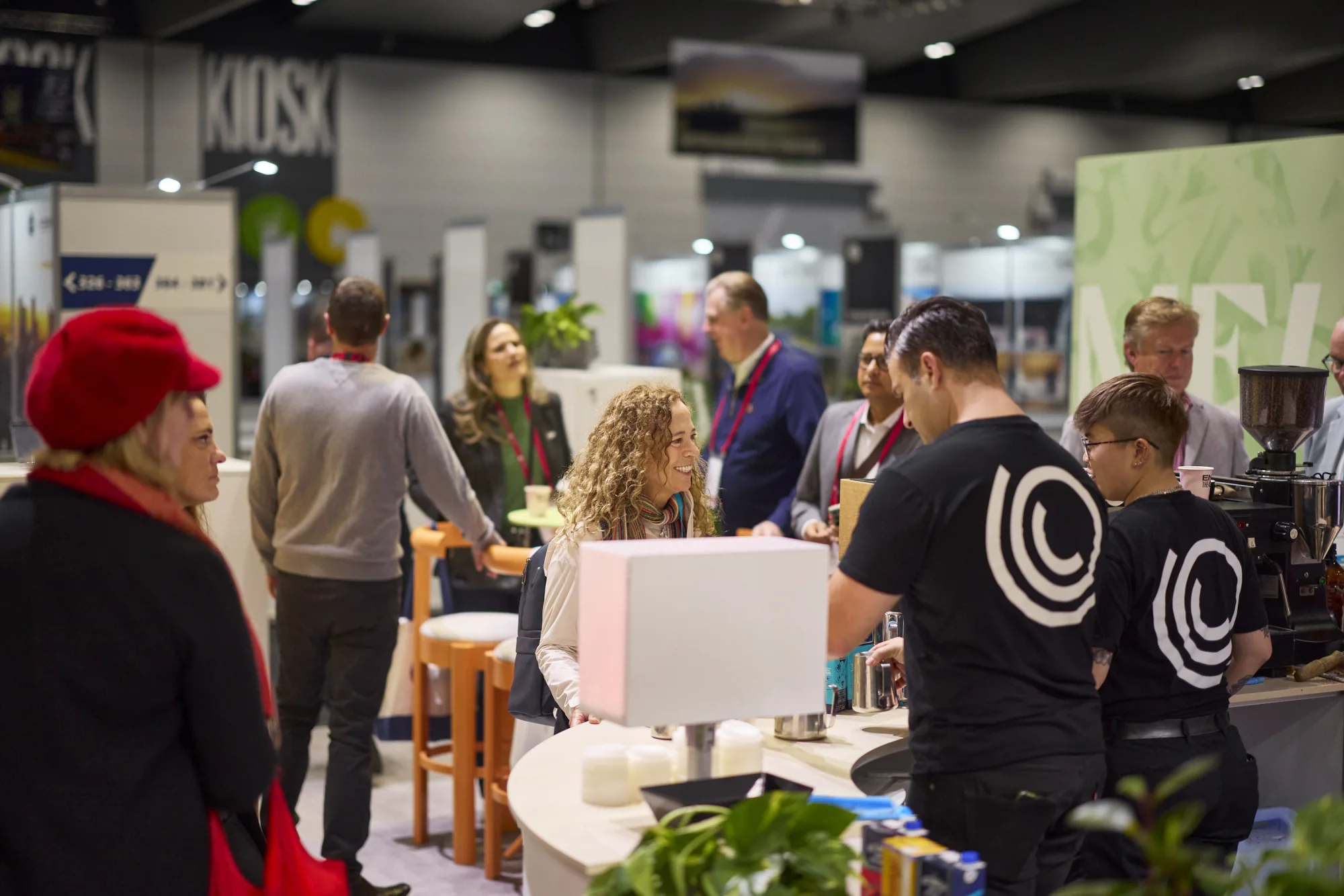 Two Coffee on Cue baristas serving conference delegates at a busy trade show coffee bar