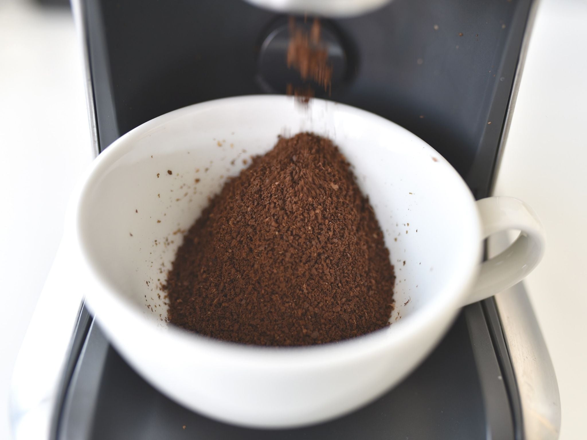 Collecting coffee grounds in cup from grinder