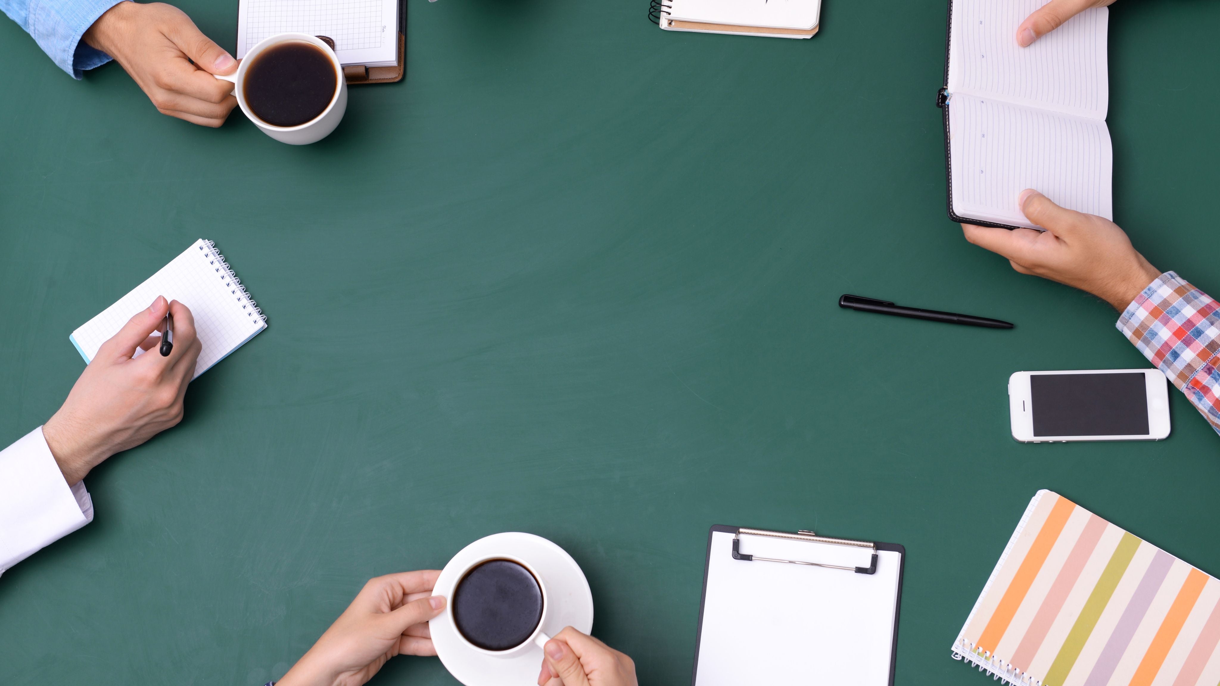 Workplace desk with cups of coffee and writing materials