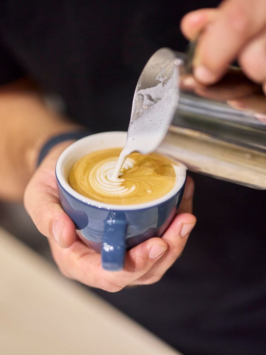 Coffee latte art being poured into a ceramic cup