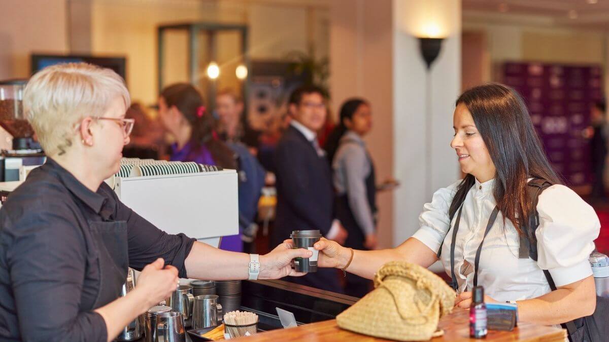 Event barista serving guest coffee at show