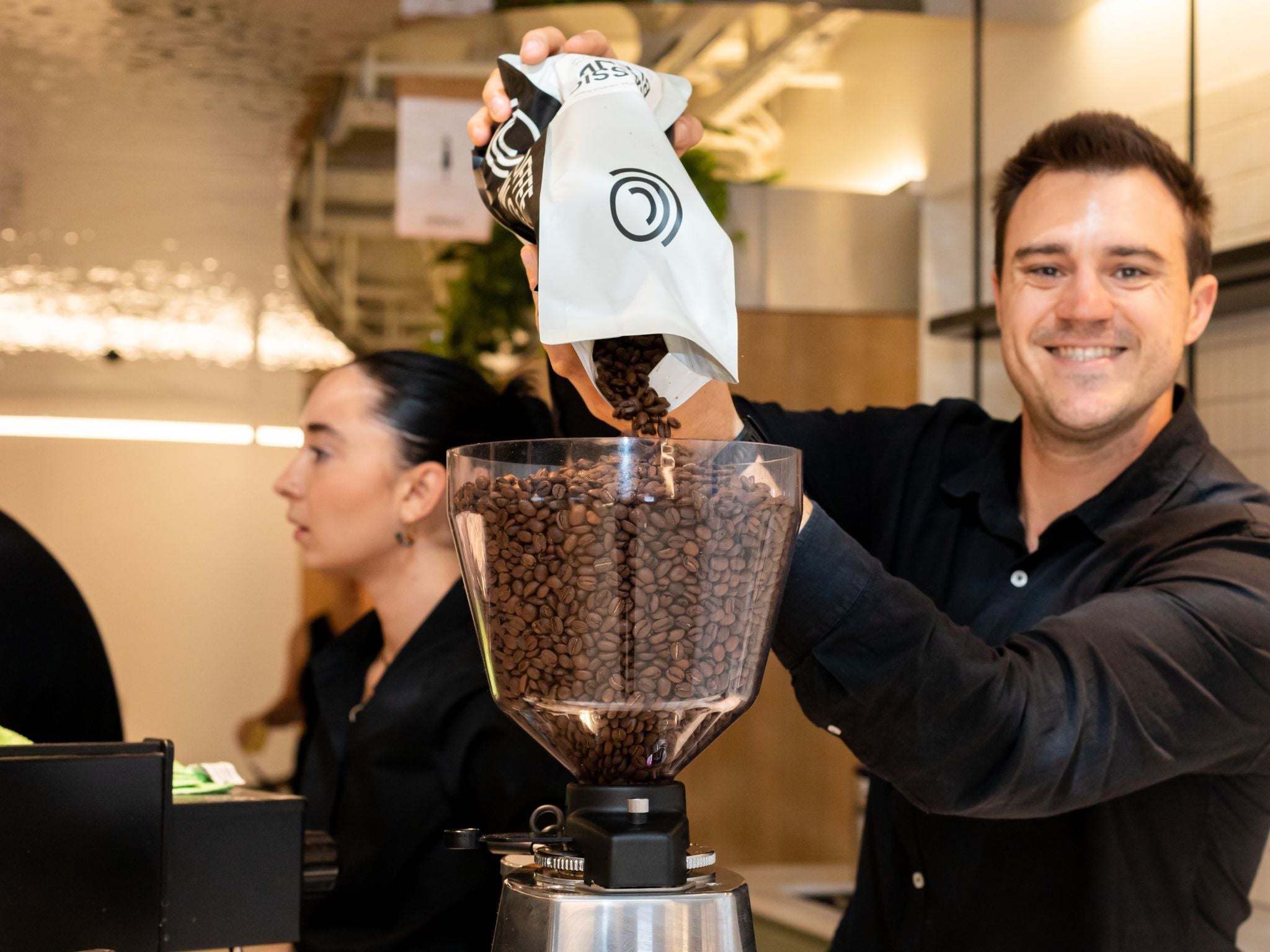 Barista filling up hopper with beans